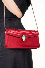 Close-up shot of the iconic Serpenti snakehead magnetic clasp, showing the light gold plating and hypnotic green emerald eyes.