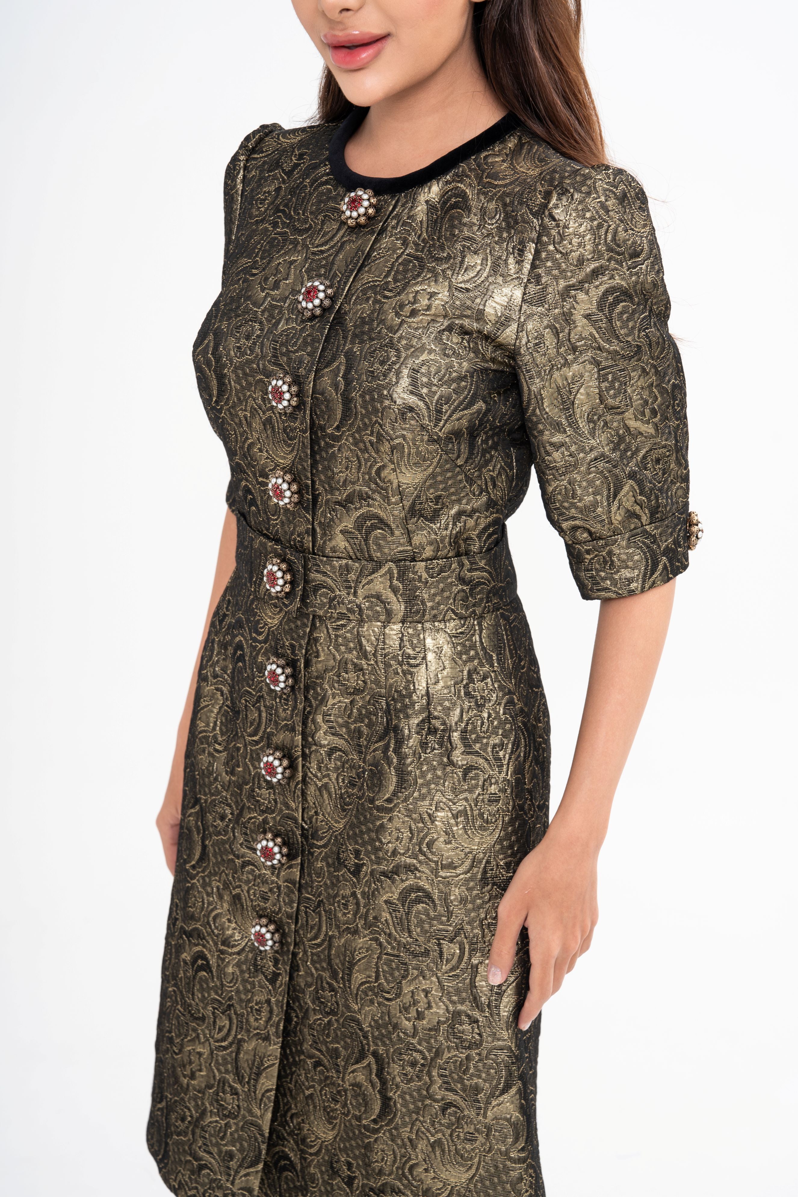 Close-up detail of the dress fabric, highlighting the textured metallic gold brocade and the velvet trim on the collar.