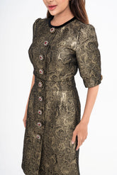 Close-up detail of the dress fabric, highlighting the textured metallic gold brocade and the velvet trim on the collar.