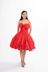 The designer dress styled, showcasing the structured fit, the gathered hemline, and the charming bow detail.