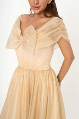 Close-up detail of the off-the-shoulder neckline, showcasing the delicate bow detail and the shimmering texture of the golden tulle.