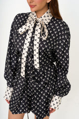 Close-up shot of the silk fabric, showing the subtle Valentino logo print and delicate pleated detailing.