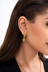 Close-up detail of the earrings, highlighting the iconic raised Medusa head motif.