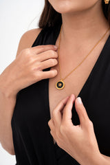 Close-up detail of the necklace pendant, highlighting the detailed Medusa logo and the Greca pattern, available for rental.