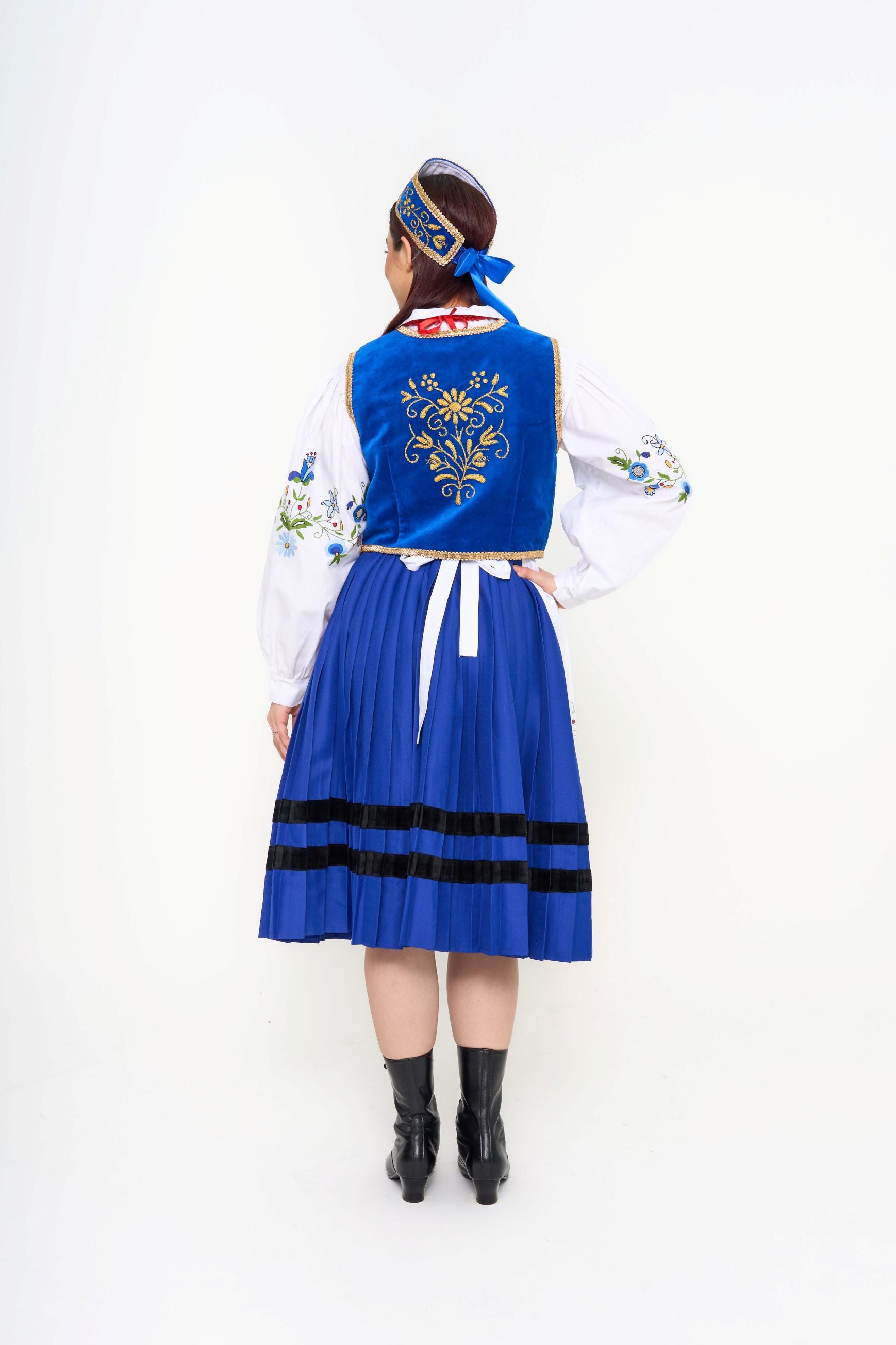 Detail of the white embroidered apron and the floral needlework on the blouse sleeve.