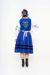 Detail of the white embroidered apron and the floral needlework on the blouse sleeve.