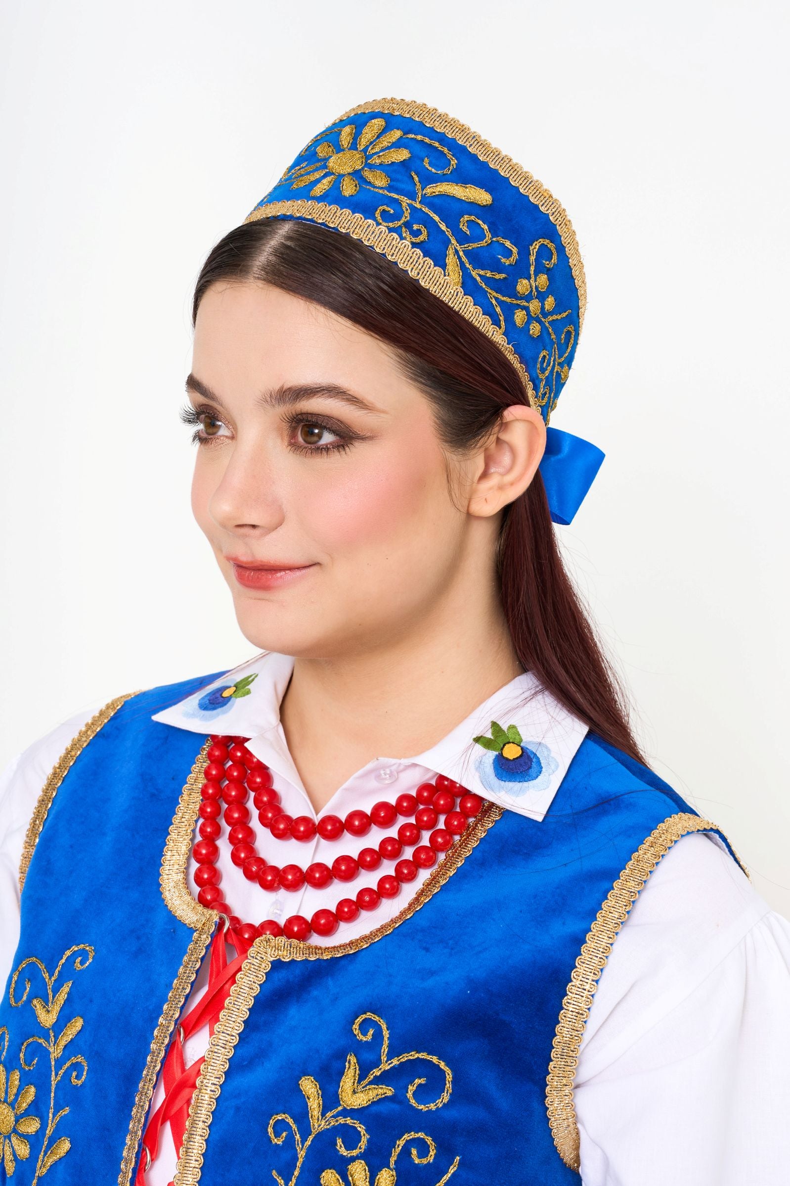 The ceremonial blue embroidered crown (headpiece) and the rich Kaszubian color palette.