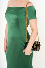 Close-up detail of the off-the-shoulder neckline and the satin-crepe fabric texture, highlighting the rich emerald colour.